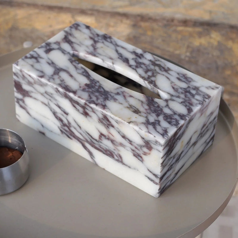 Marble-patterned tissue box on a round table with a blurred background
