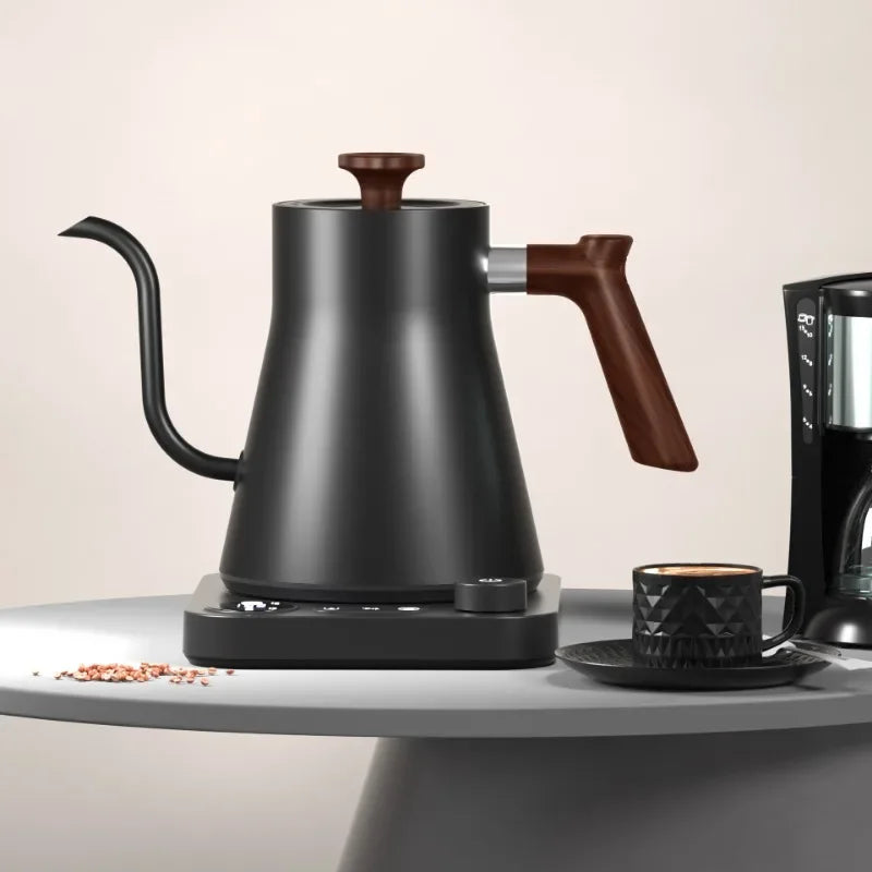 A matte black electric gooseneck kettle with wooden accents and a digital base, next to a small black mug with a geometric pattern.