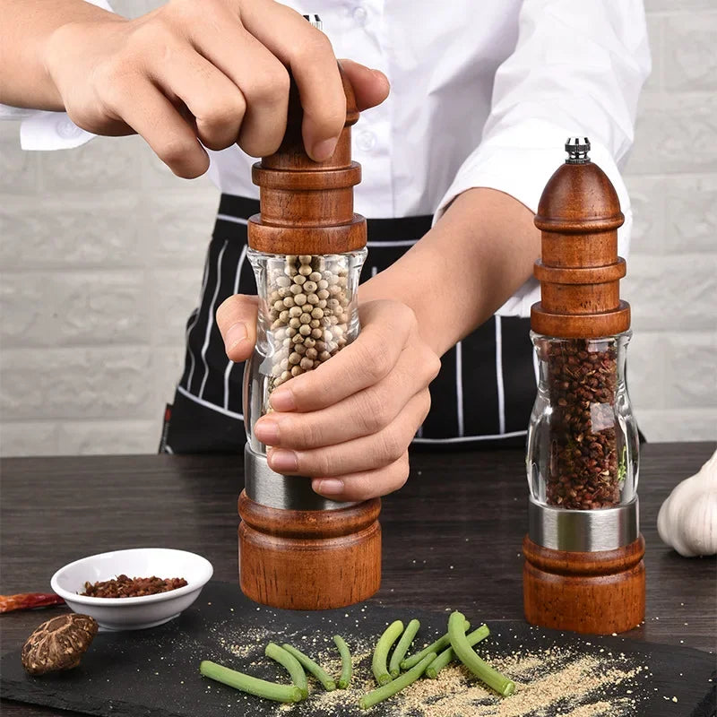 Person using a wooden pepper grinder with a clear container on a table with ingredients.
