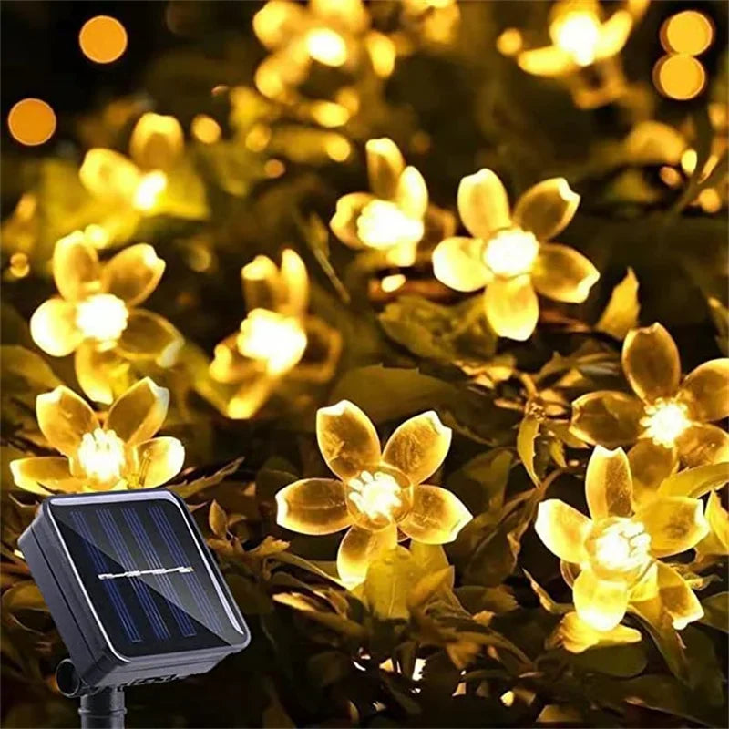 Solar-powered yellow LED flower string lights and solar panel in foliage.