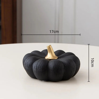A small black decorative pumpkin with a gold stem with dimensions