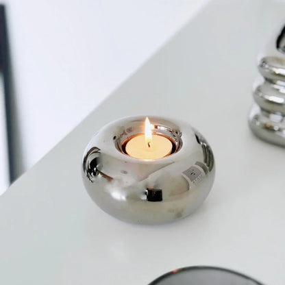Silver candle holder with a lit candle on a white surface