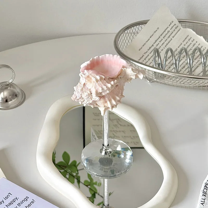 Decorative pink shell on a stand with a heart-shaped mirror in the background
