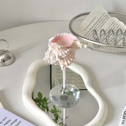 Decorative pink shell on a stand with a heart-shaped mirror in the background