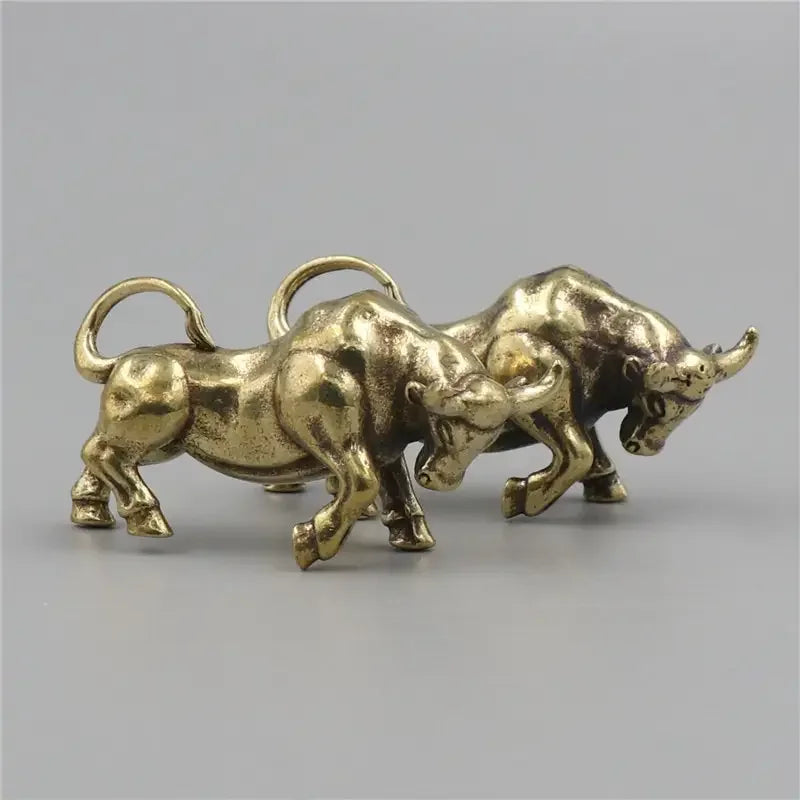 Two gold bull figurines on a gray background