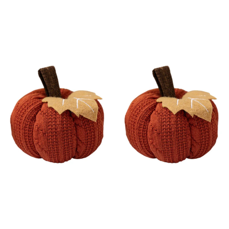 Two identical orange knitted pumpkins, each with a brown stem and a beige felt leaf, isolated on a white background.