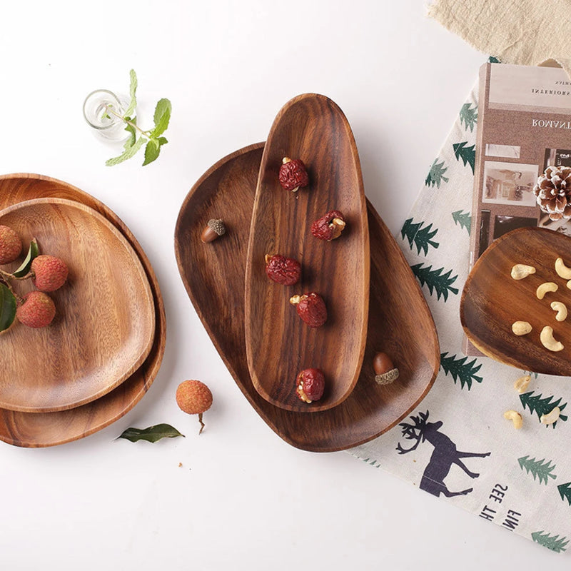 A collection of various wooden serving trays with a book, nuts, and fresh fruit.