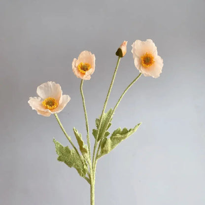 Three white yellow poppy flowers with green stems and one poppy bud are arranged in a sparse bouquet against a plain light grey background.