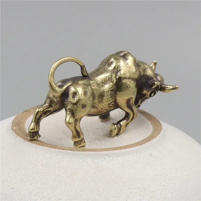 Bronze bull figurine on a white stand with a gray background