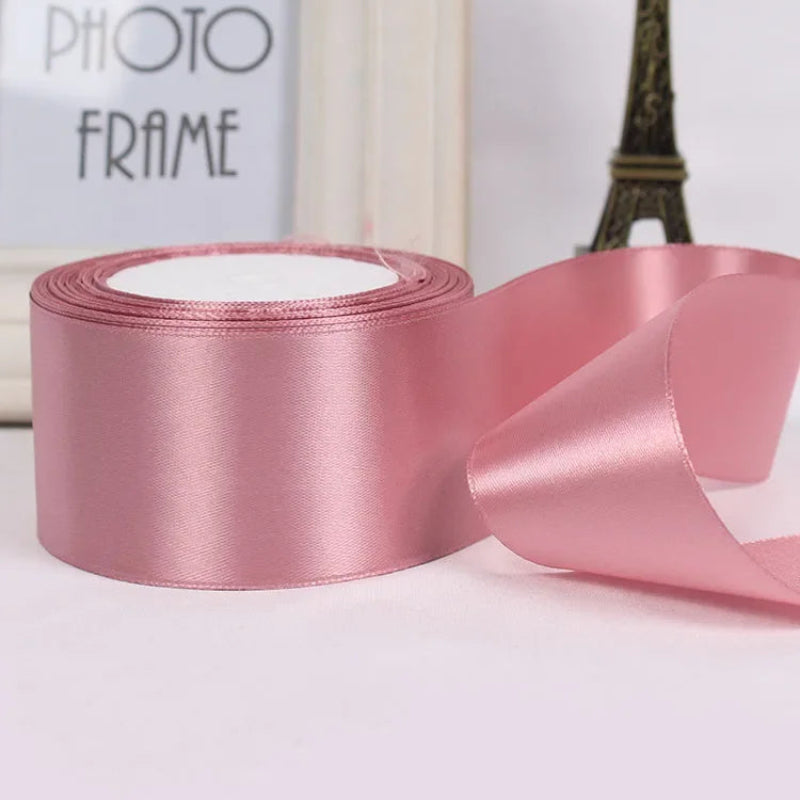 Roll of pink satin ribbon with a blurred photo frame and Eiffel Tower in the background