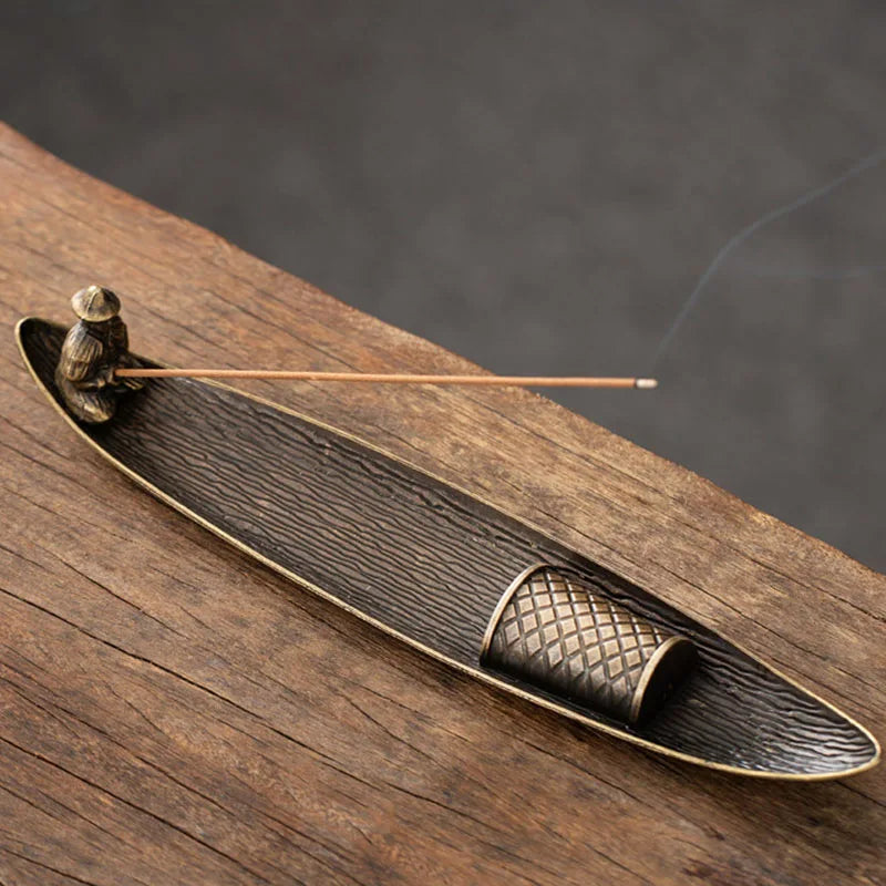 Bronze incense burner with incense stick on a wooden surface