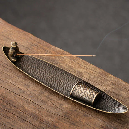 Bronze incense burner with incense stick on a wooden surface