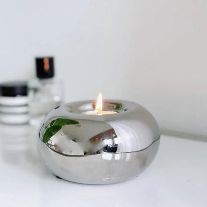 Silver candle holder with a lit candle on a white surface