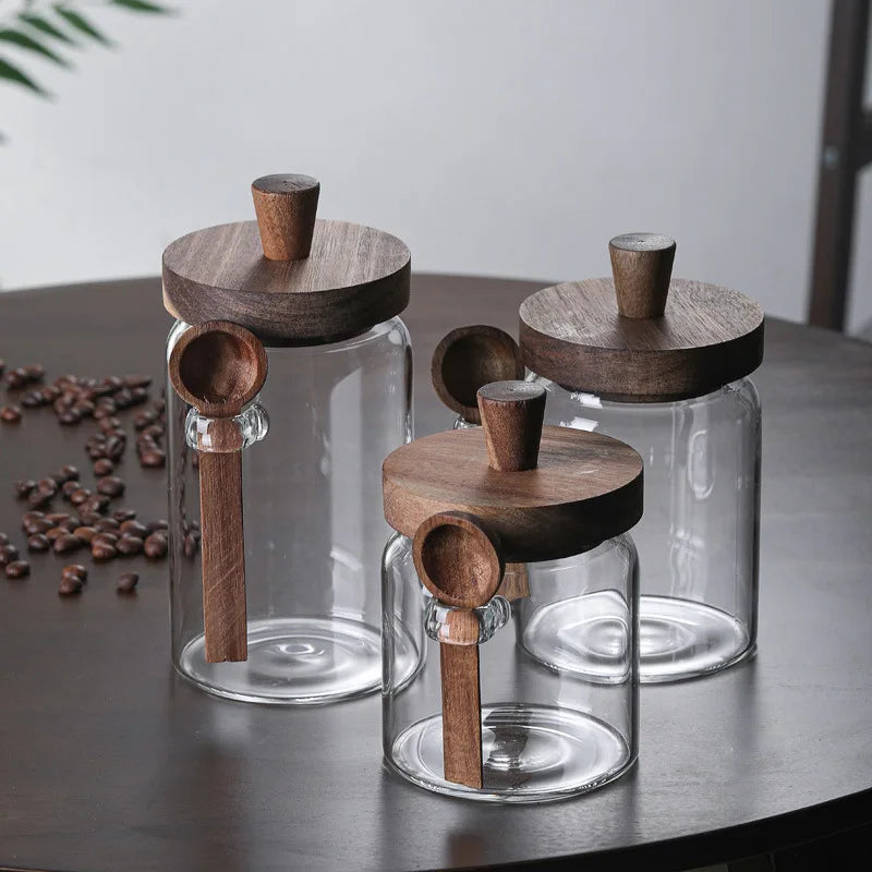 Three glass jars with wooden lids on a dark surface with coffee beans.