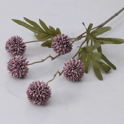 A single stem of artificial purple dahlia flowers with green leaves.