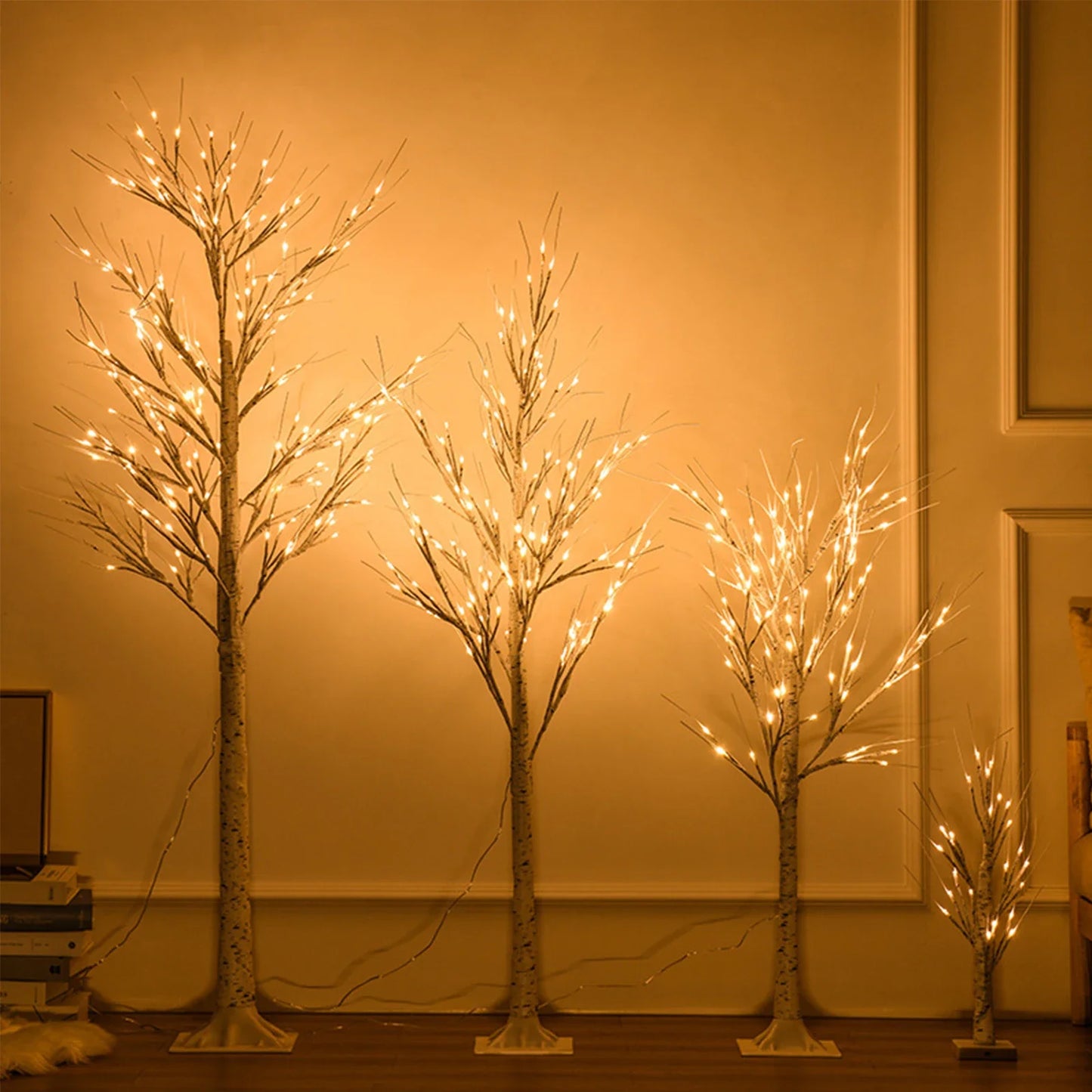 Set of four illuminated decorative trees against a plain wall.