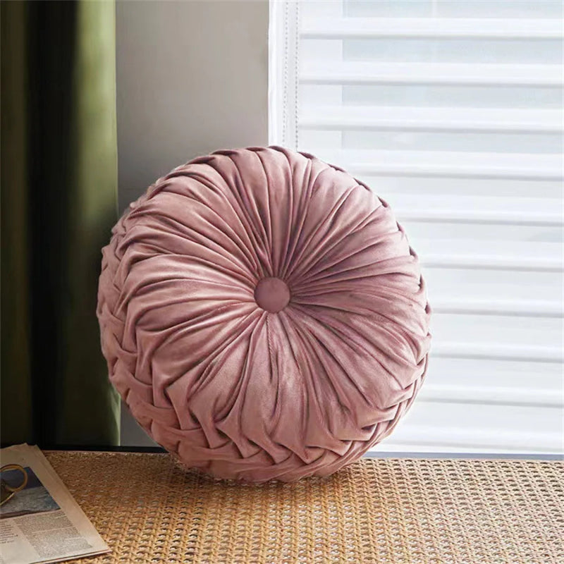 Round pink pillow on a textured surface with a window in the background