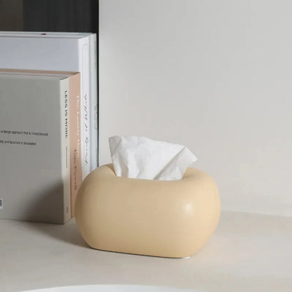 A donut-shaped, tissue box holder sits on a counter next to a stack of books.