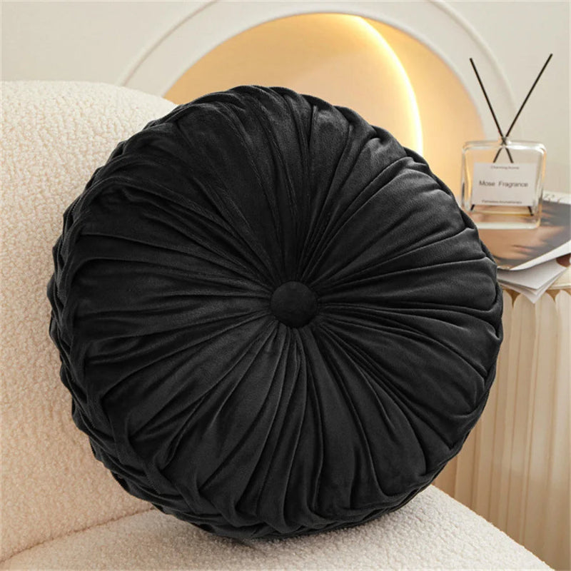 Black round pillow on a beige couch with a blurred background