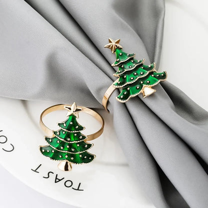 Two green Christmas tree-shaped rings with gold accents on gray fabric.