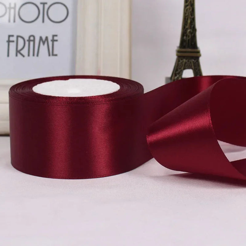 Red satin ribbon with a partially unrolled section on a light background