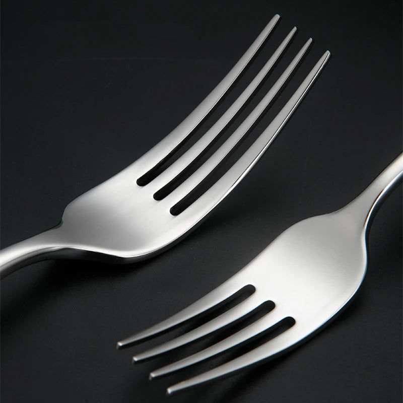 Two silver forks on black surface