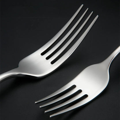 Two silver forks on black surface