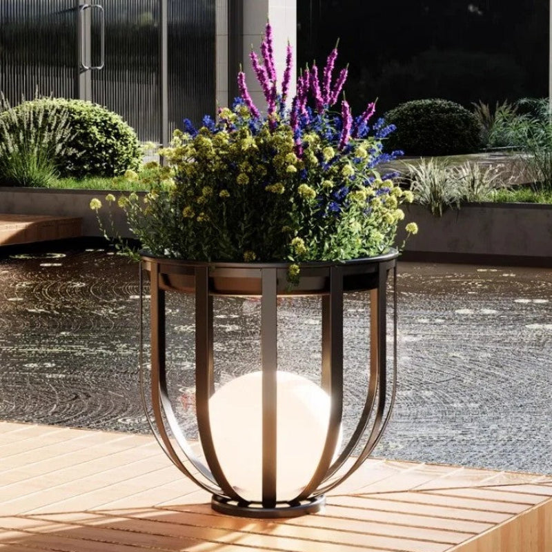 Decorative outdoor planter with flowers and a light fixture on a wooden deck.