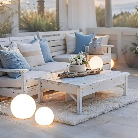 Outdoor patio with white furniture, blue and white cushions, and decorative lights.