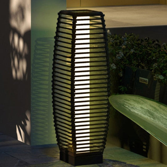 Woven outdoor lamp with a bench and plant in the background