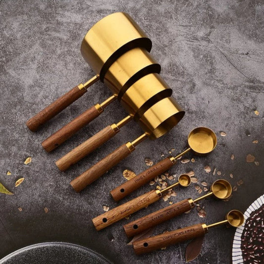 Set of gold and wooden measuring cups and spoons on a textured surface