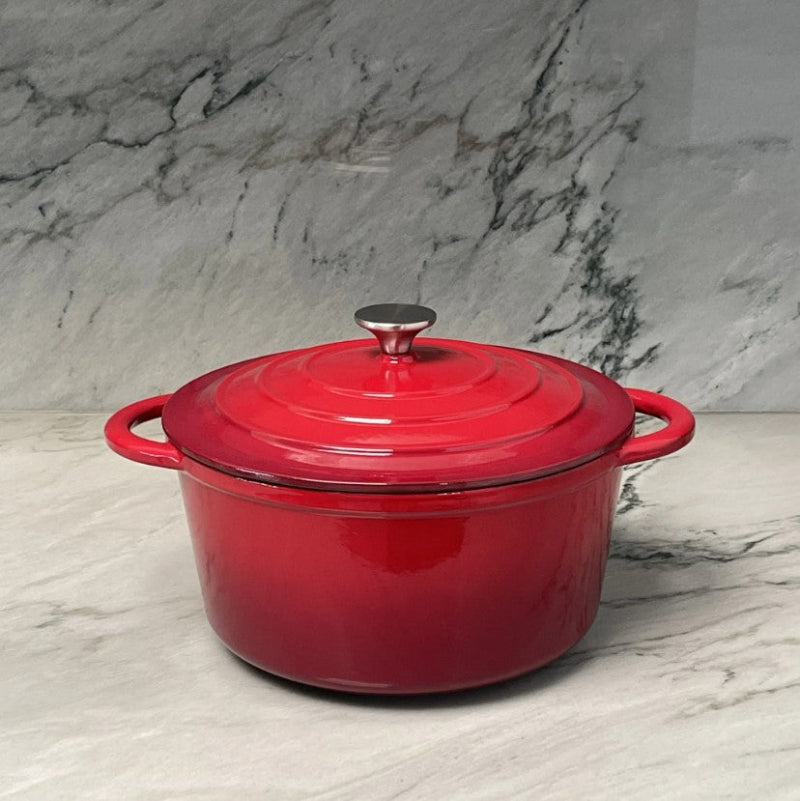 Red enameled cast iron Dutch oven on a marble surface