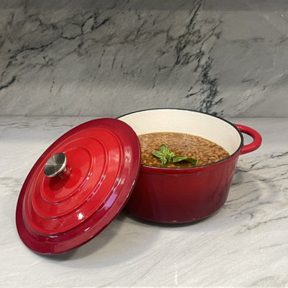 Red enameled cast iron cookware with a lid on a marble surface