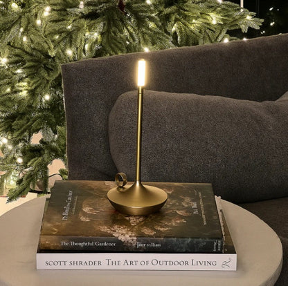 Gold candlestick lamp on a book with a Christmas tree in the background