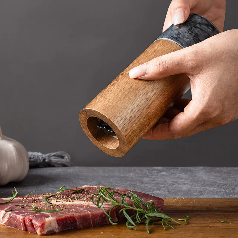 A hand grinding spices onto a raw steak.
