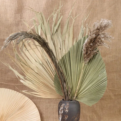 Palm fan leaf set paired with neutral ceramics and greenery, enhancing a boho-themed interior aesthetic.