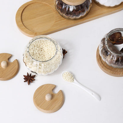 Close-up of a pumpkin-shaped glass jar filled with white sesame seeds, with wooden lids and star anise.