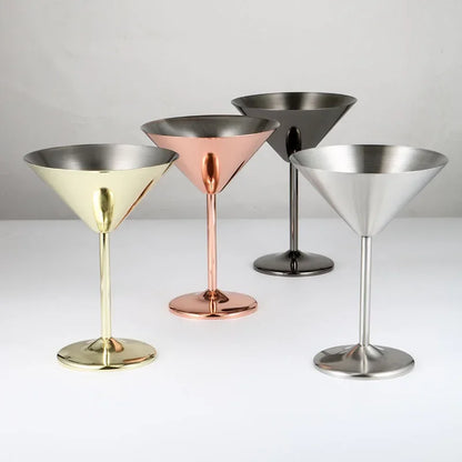 A set of four metal martini glasses in gold, copper, black, and silver finishes.
