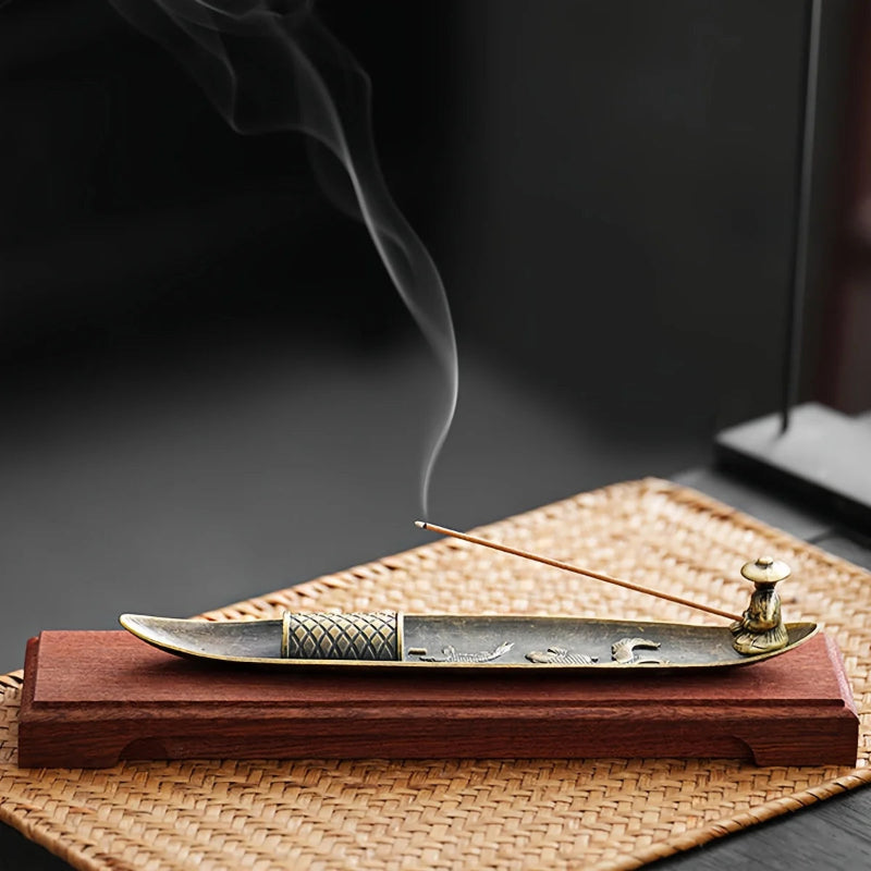 Incense stick burning on a tray with smoke against a dark background