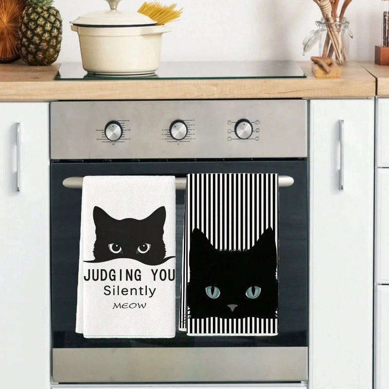 Kitchen oven with black and white cat-themed towels hanging on the handle