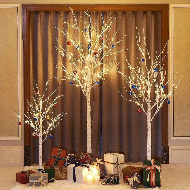 Decorative trees with lights and ornaments in a room with gift boxes and candles.