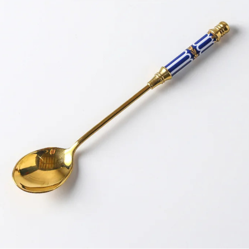 Gold spoon with blue and white handle on a white background