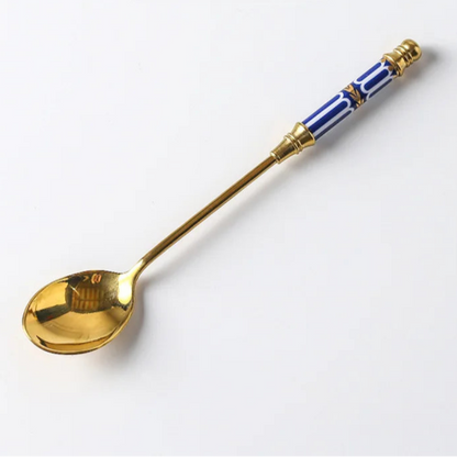 Gold spoon with blue and white handle on a white background