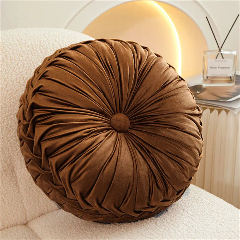 Brown round pillow on a white surface with a blurred background