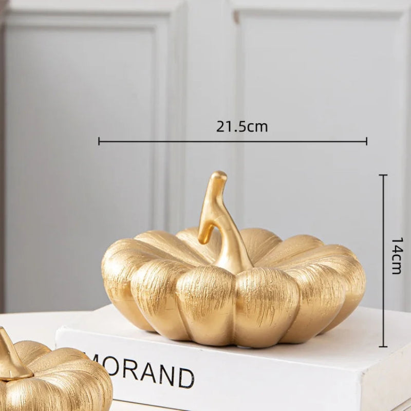 A golden decorative pumpkin with a matching stem, resting on a book.