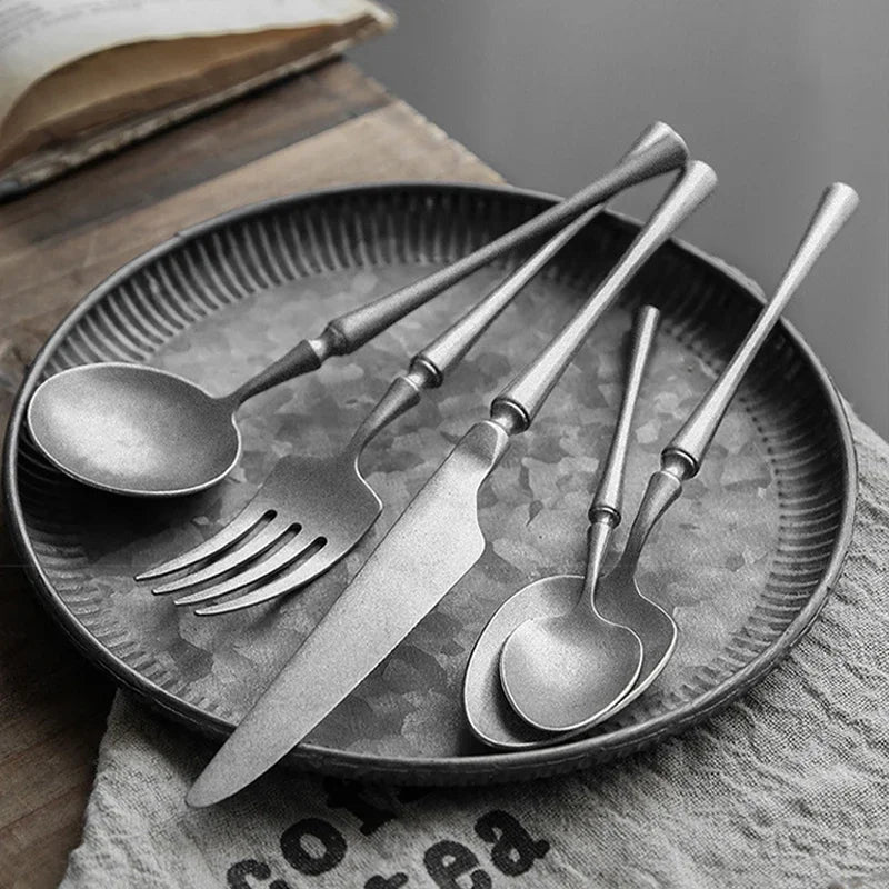 Set of silver cutlery on a textured plate with a book in the background