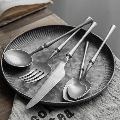 Set of silver cutlery on a textured plate with a book in the background