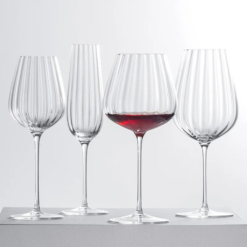 Four fluted glasses, one with red wine.