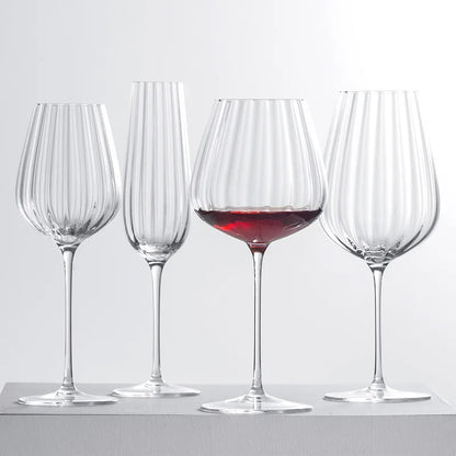 Four fluted glasses, one with red wine.