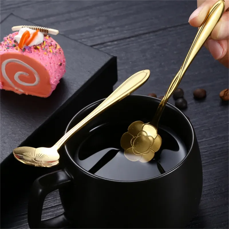 A hand stirring coffee with a golden flower spoon, next to a pink cake.